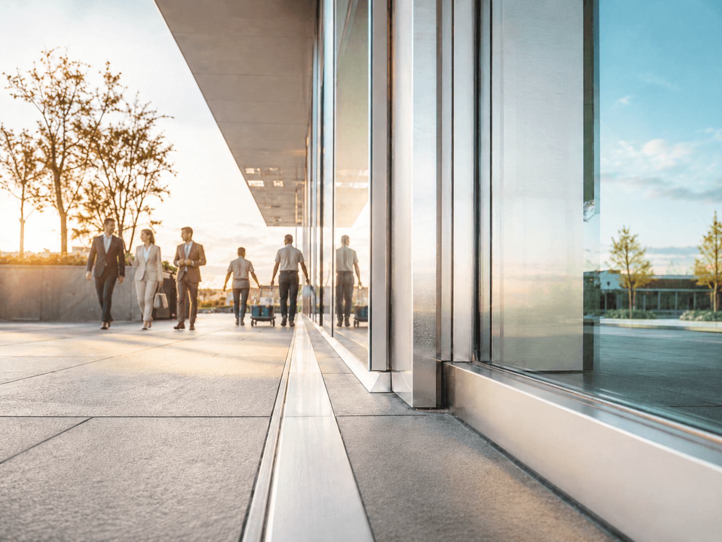 Professionals walking through a glass-walled lobby at golden hour