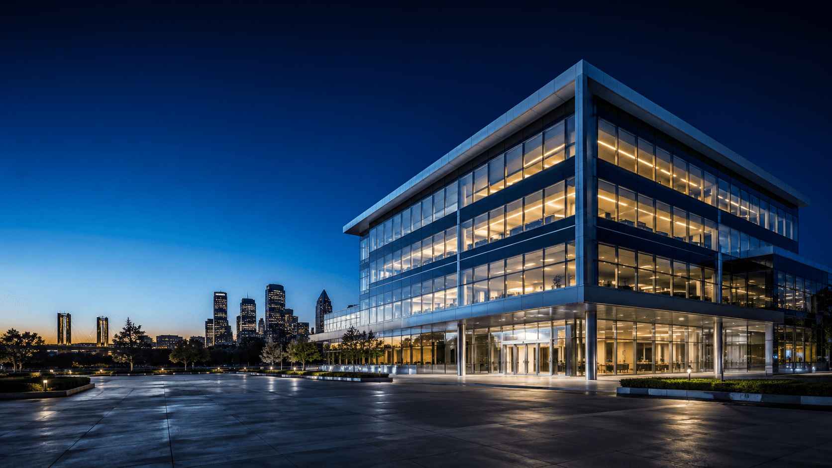 Glass office tower at dusk, lights reflecting
